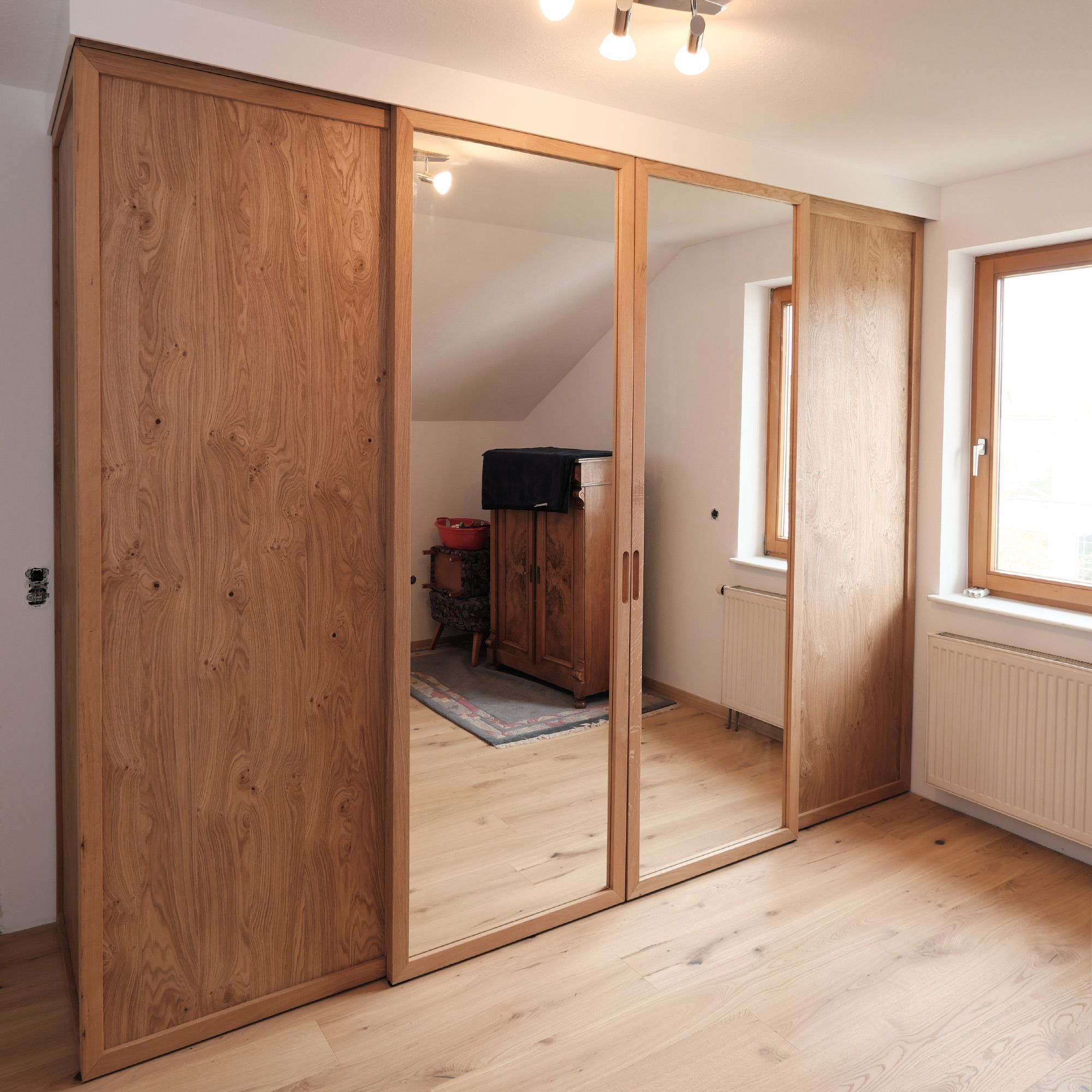 Eichenholz-Kleiderschrank mit Spiegel-Schiebetüren unter Dachschräge im Schlafzimmer