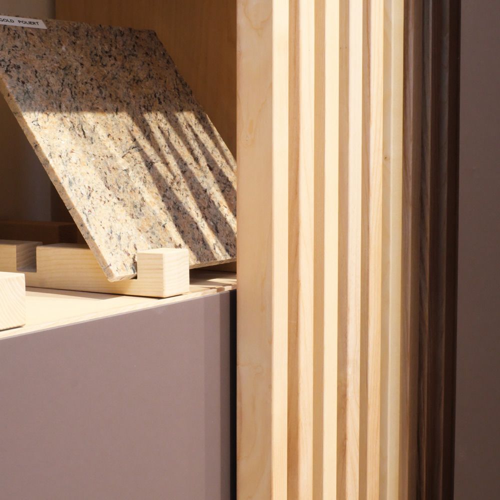 Musterausstellung mit poliertem Granit und Holzlamellen verschiedener Holzarten bei Holzfreude