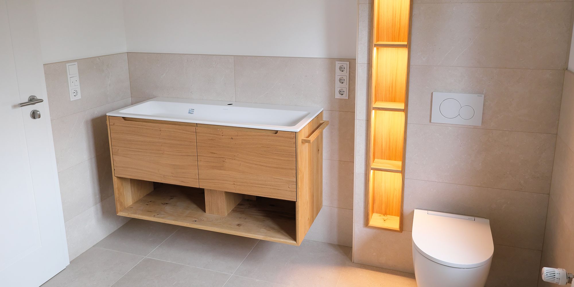 Modernes Badezimmer mit schwebendem Eiche-Waschtisch, Mineralwerkstoff-Becken und beleuchteter Wandnische