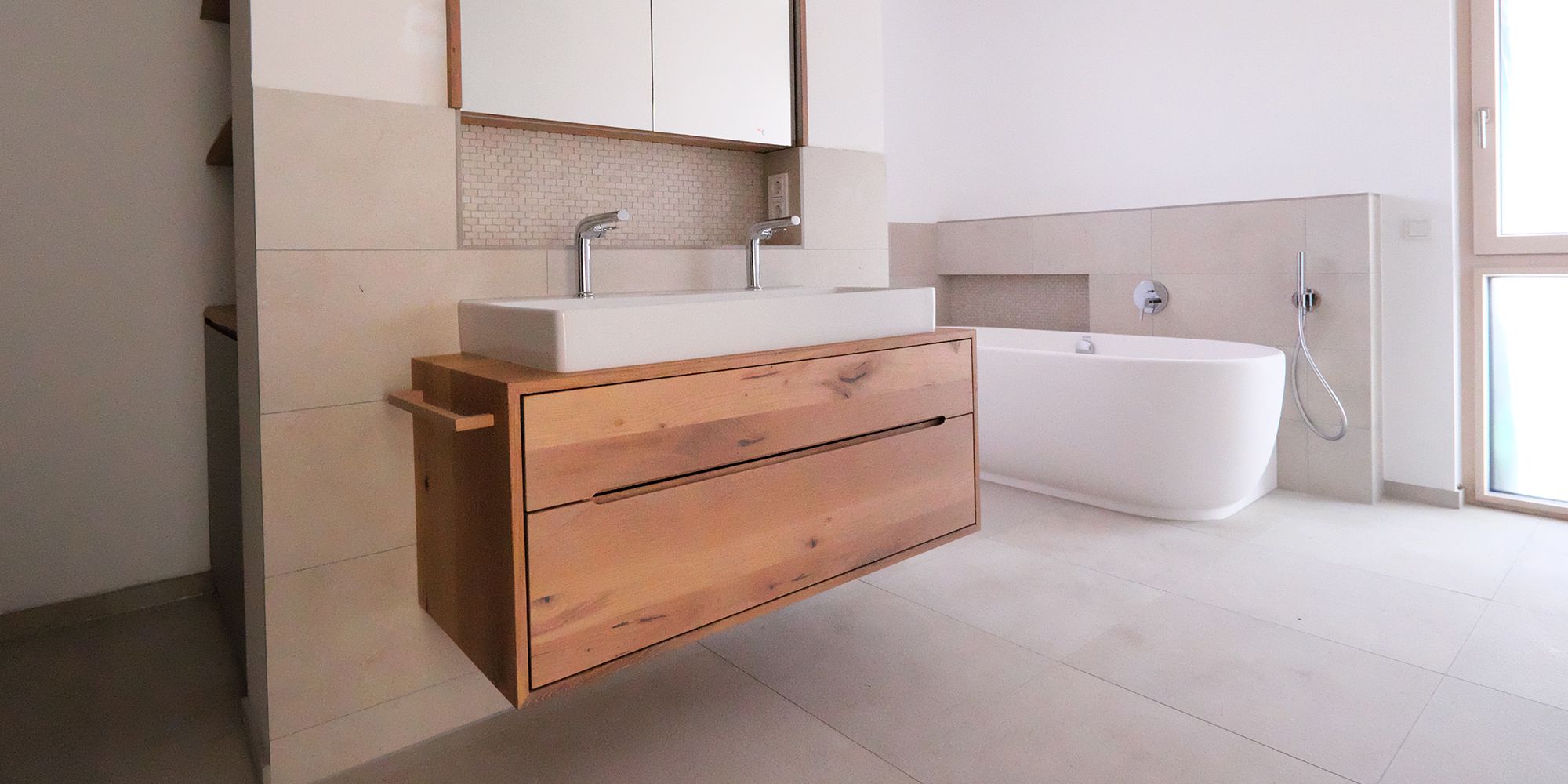 Badezimmer mit Eichen-Waschtisch, Doppelwaschbecken und freistehender Badewanne im Hintergrund