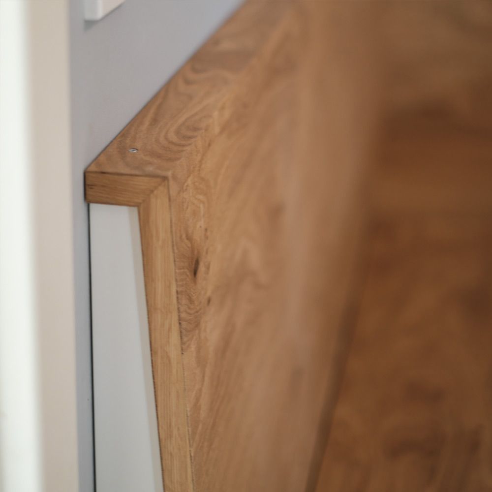 Detailaufnahme der Eckverbindung einer Eichenholz-Rückenlehne über weißem Sockel