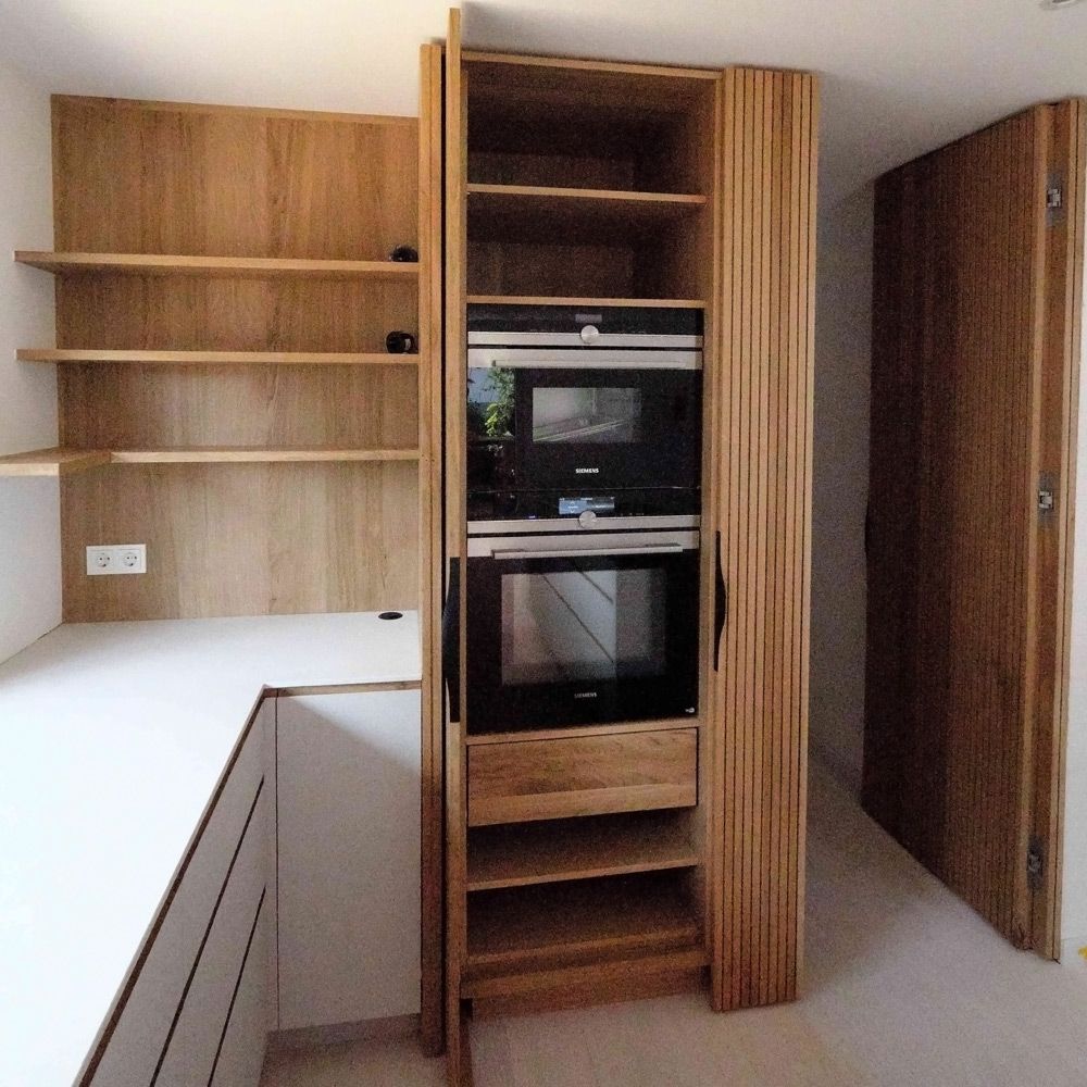 Hochschrank mit Eichen-Lamellen-Drehschiebetür und eingebauten Backöfen in offener Küche