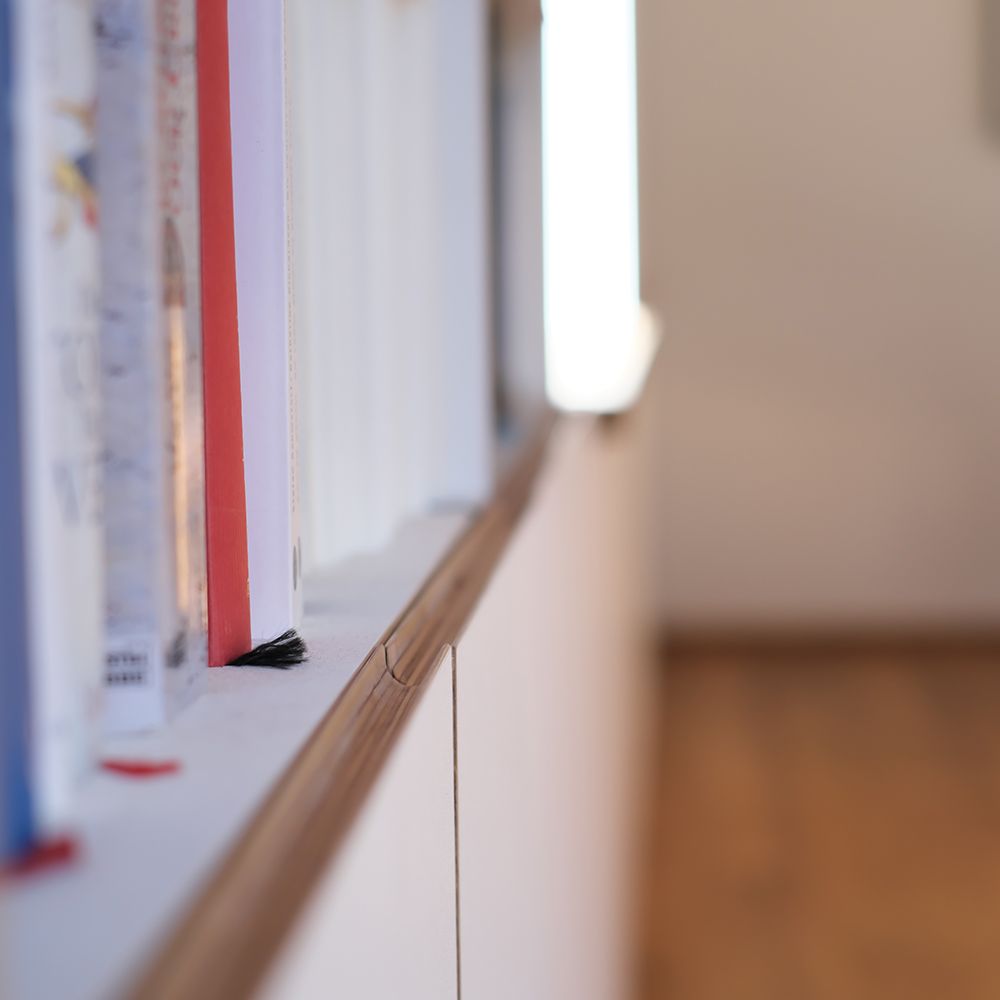 Nahaufnahme einer Eiche-Griffleiste am weißlackierten Bücherregal-Einbauschrank