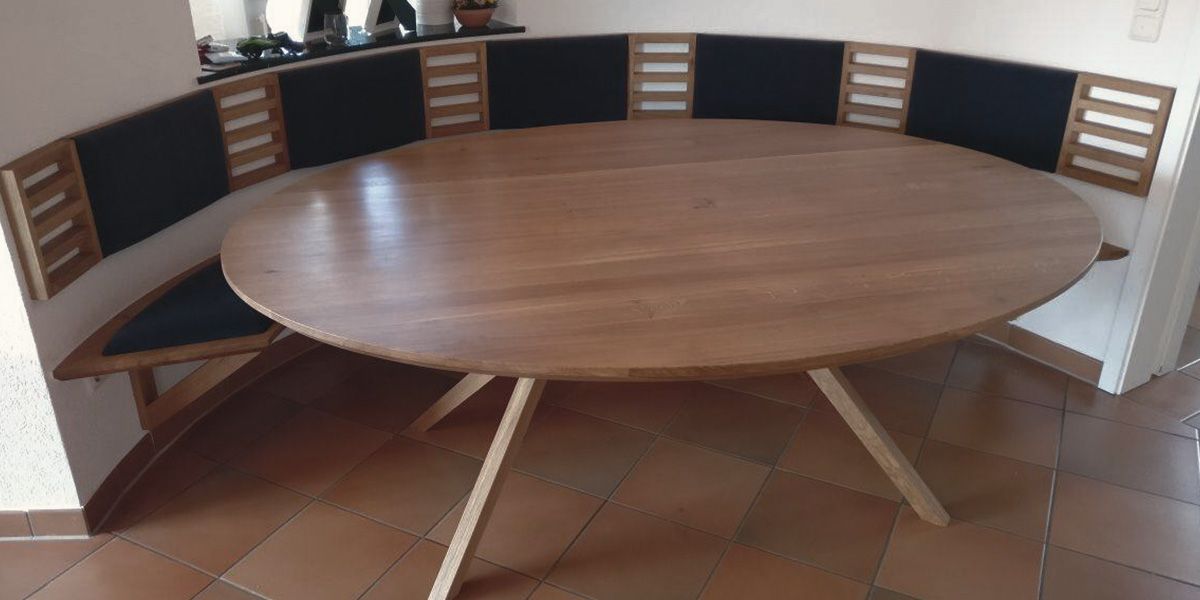 Elliptischer Massivholztisch aus Eiche mit gekreuzten Beinen und wandintegrierter Eckbank in Essecke