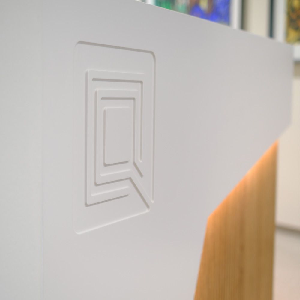 Detail der weißen Mineralwerkstoff-Theke mit graviertem Logo neben Eichenlamellen
