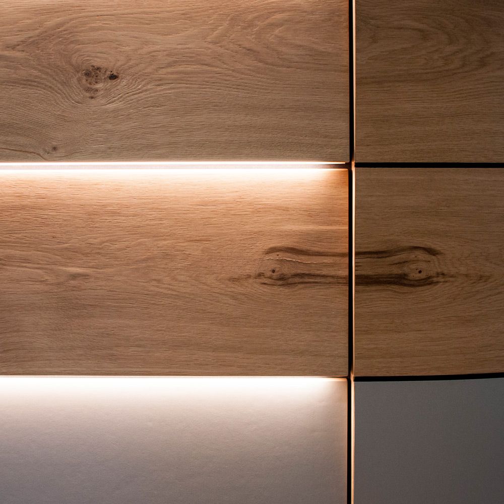 Eichenholz-Fronten mit warmer LED-Lichtfuge und markanter Maserung im Detail