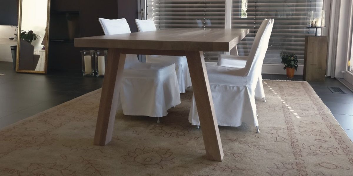 Esstisch aus weiß geölter Massivholz-Eiche mit Schrägbeinen auf edlem Teppich im Wohnbereich