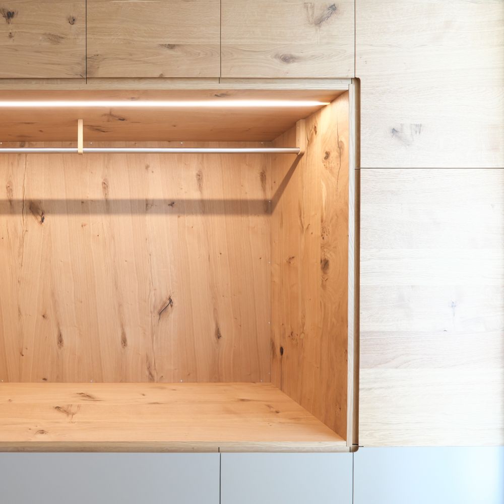 Offenes Fach einer Eiche-Garderobe mit Kleiderstange und integriertem LED-Lichtband