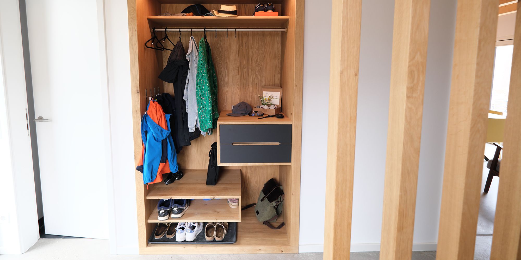 Offene Eiche-Garderobe mit Kleiderstange, Schubladen und Schuhablage hinter Holzlamellen