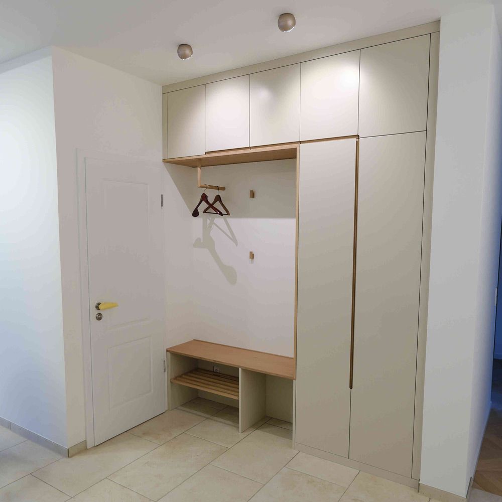 Helle cremefarbene Einbau-Garderobe mit offener Kleiderstange, Sitzbank und Schuhregal im Flur