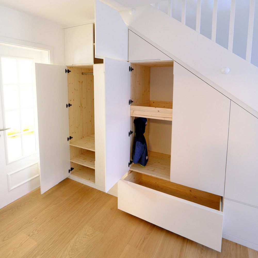 Weißlackierter Treppenschrank mit offenen Türen und hellem Fichte-Innenausbau als Garderobe im Flur