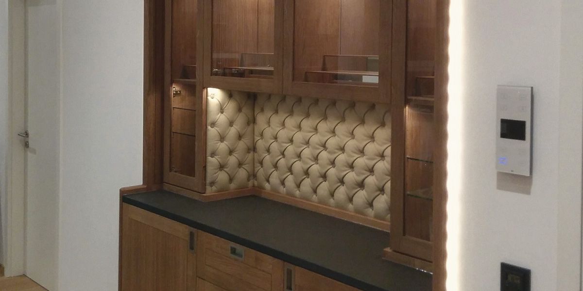 Klassische Hausbar aus Eiche mit Natursteinplatte, Leder-Chesterfield-Rückwand und beleuchteter Glasvitrine