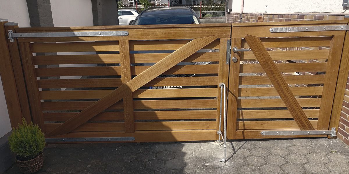 Zweiflügeliges Hoftor aus Eichenholz mit diagonaler Verstrebung und Metallbeschlägen an einer Einfahrt