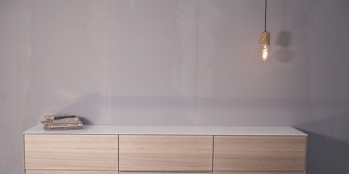 Pendelleuchte Fitis aus Holz über hellem Sideboard in minimalistischem Wohnraum
