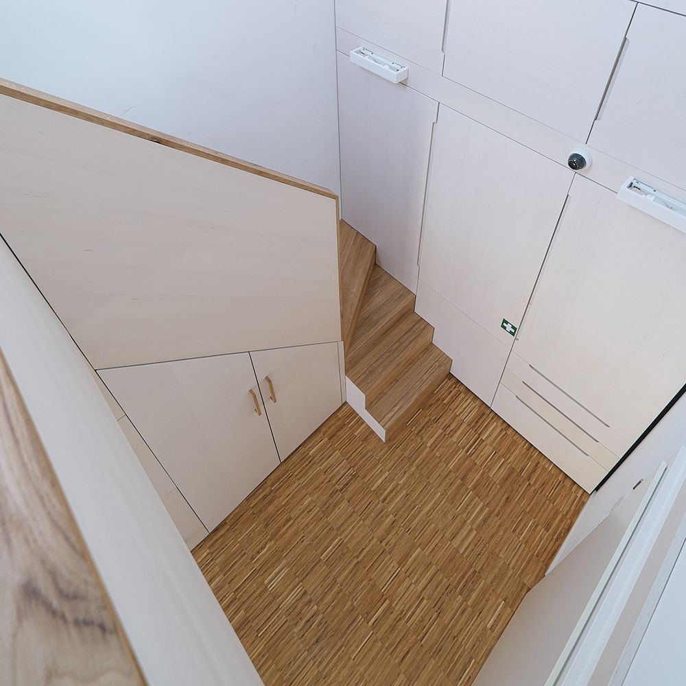 Treppenhaus mit weiß geölten Einbauschränken unter der Dachschräge und Eichen-Stabparkett von oben