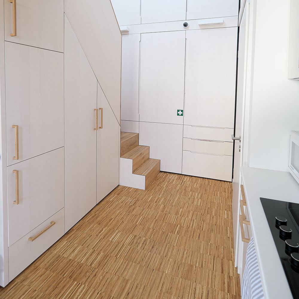 Raumhohe weiß geölte Einbauschränke mit Holzgriffen neben Treppe und Küchenzeile auf Eichenparkett