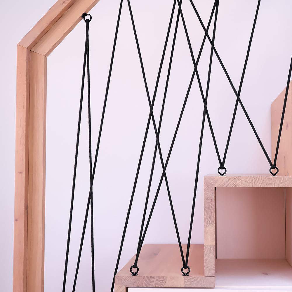 Detailaufnahme des schwarzen Kreuz-Seilgeländers mit Ösen an Treppenstufen aus Massivholz