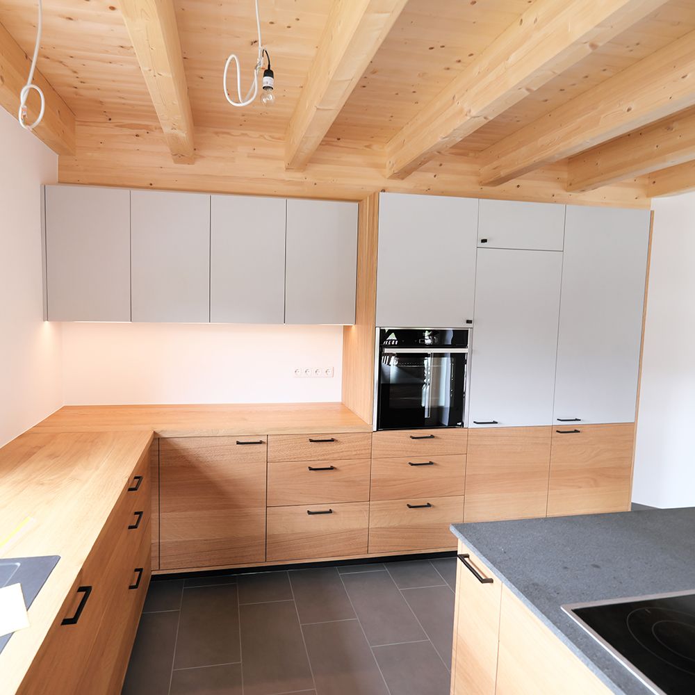 U-Küche mit ruhigem Eichenfurnier und weißen Oberschränken unter Holzbalkendecke