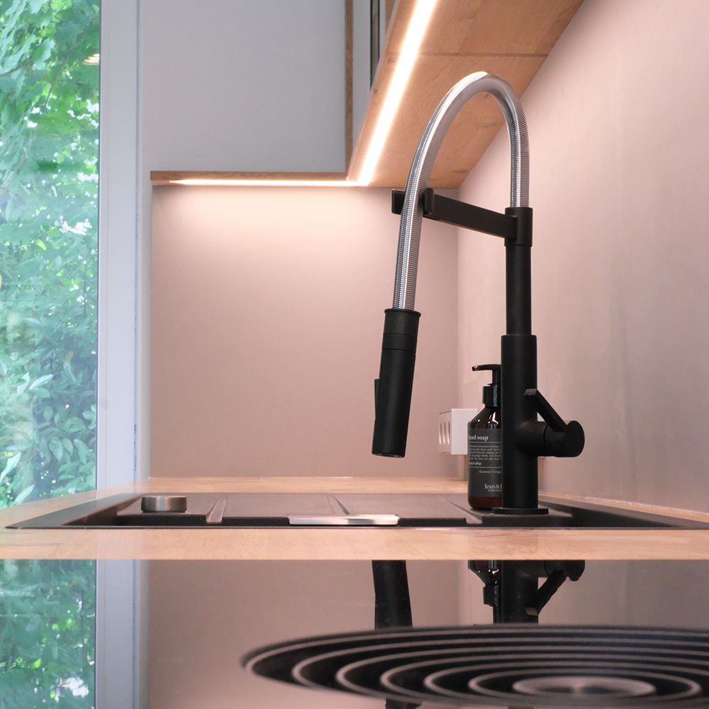 Schwarze Design-Armatur mit Auszugsbrause über Spüle und Muldenlüfter