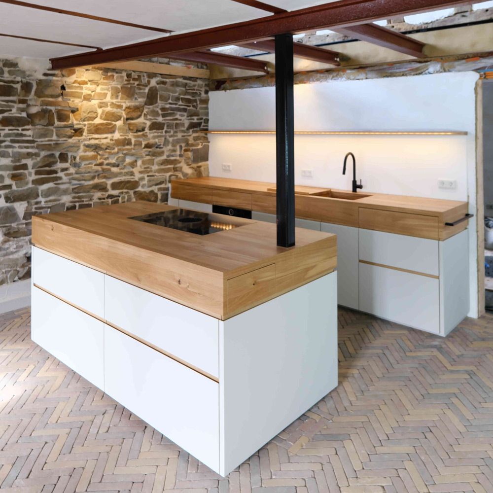 Kücheninsel mit Kochfeld und Eichenholz-Arbeitsplatte in rustikalem Loft mit Steinwand
