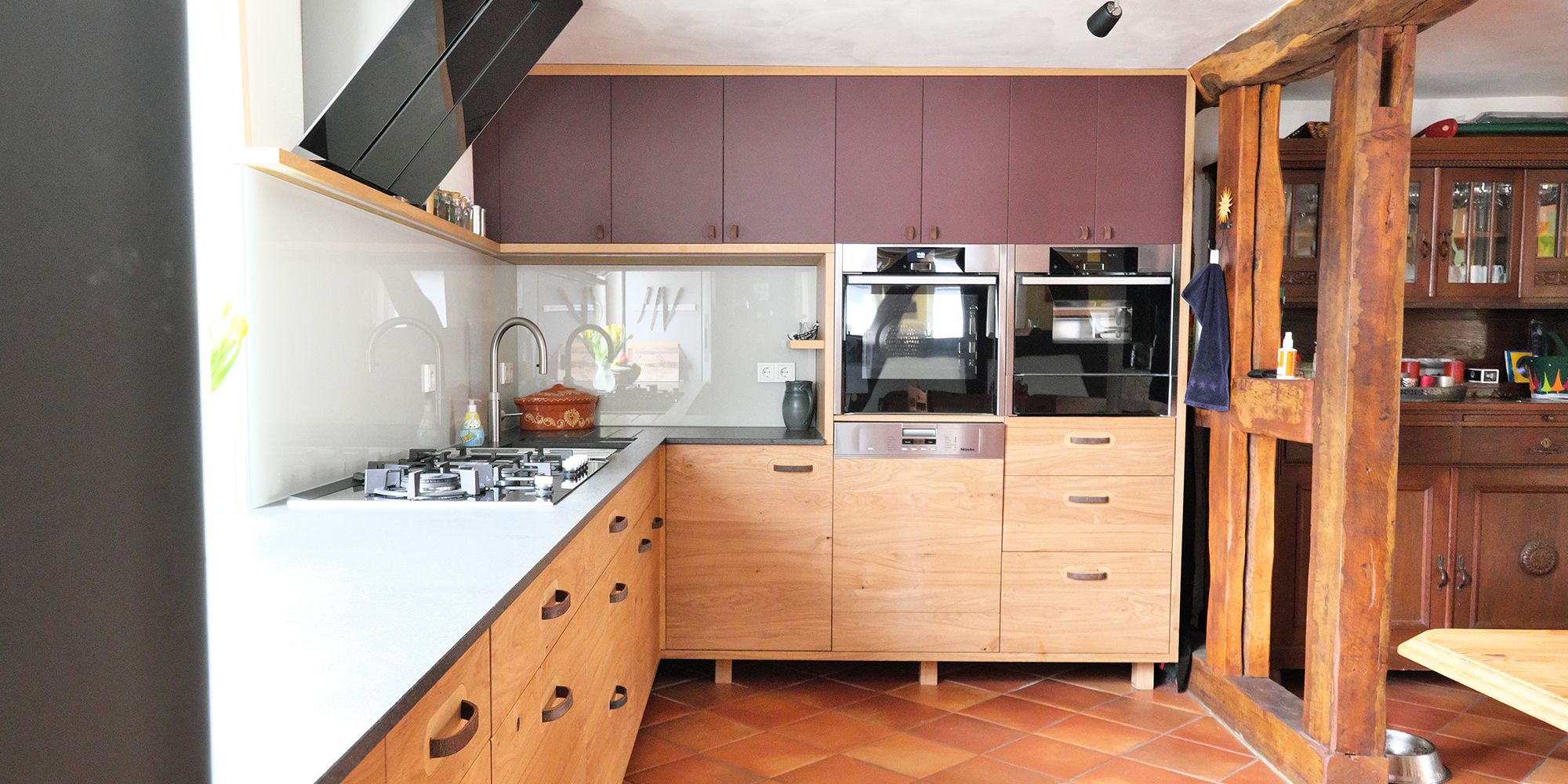 Massivholzküche in Eiche mit aubergine Oberschränken, Dunstabzug und Blick ins Fachwerk-Nebenzimmer