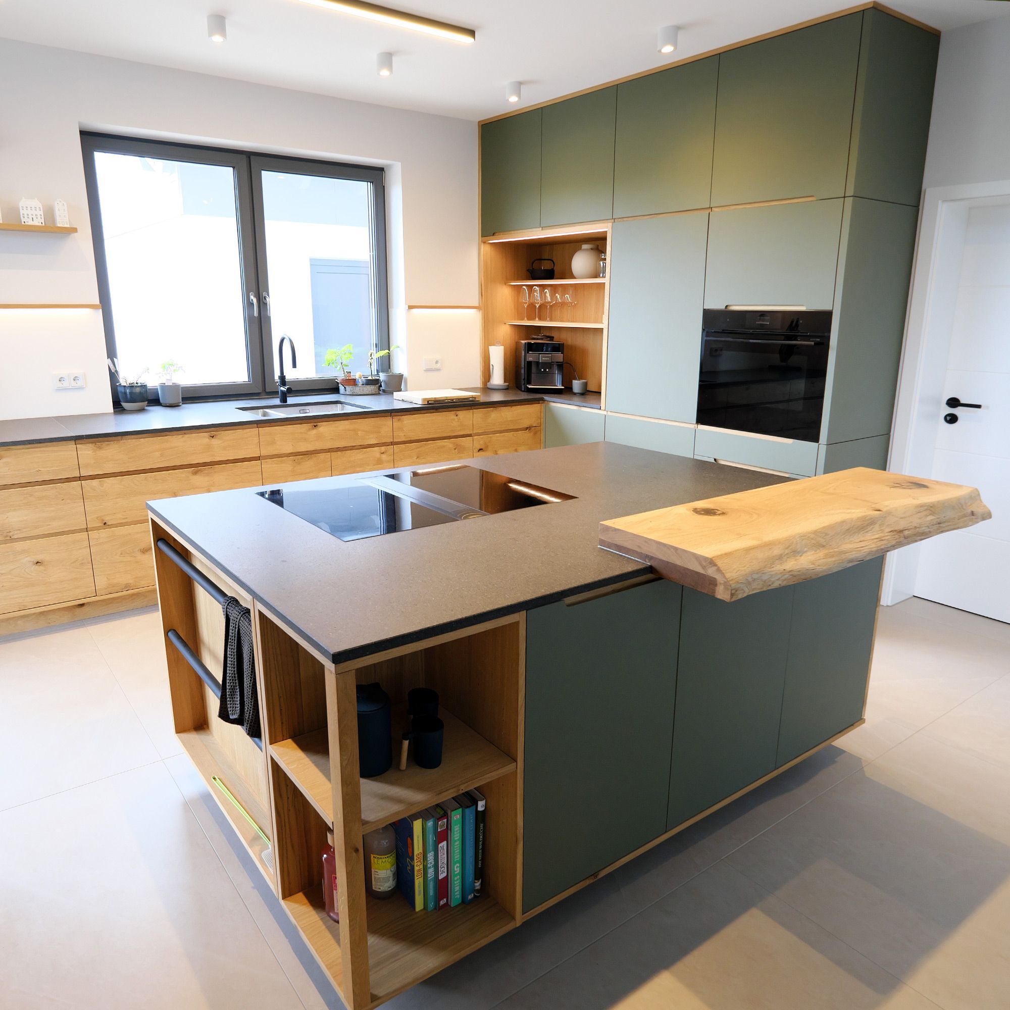 Offene Küche mit Kochinsel, Baumkante aus Eiche und olivgrünen Fronten in Landhausoptik