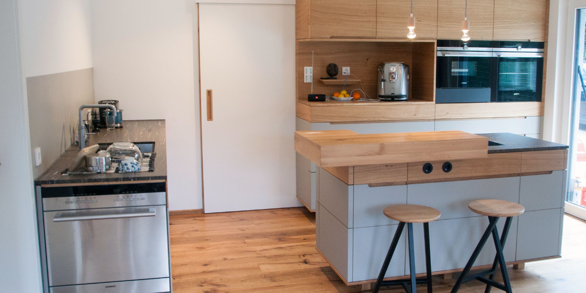 Moderne Kücheninsel aus Eiche mit dunkler Linoleum-Arbeitsplatte und zwei Barhockern