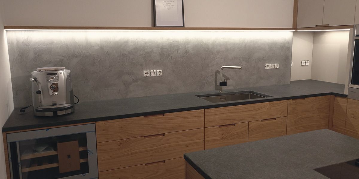 Eiche-Küche mit Granit-Arbeitsplatte, Betonoptik-Rückwand, Edelstahlspüle und indirekter LED-Beleuchtung