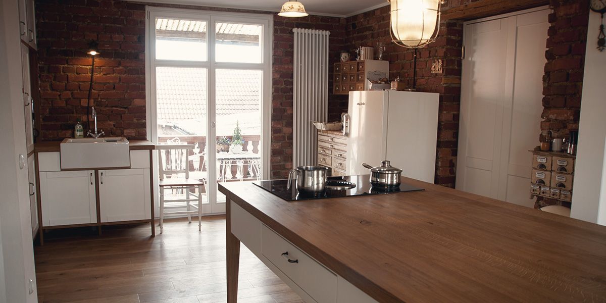 Landhausküche mit freistehender Tischinsel aus Eiche, Ziegelwand und Retro-Küchenmöbeln in Altbauwohnung