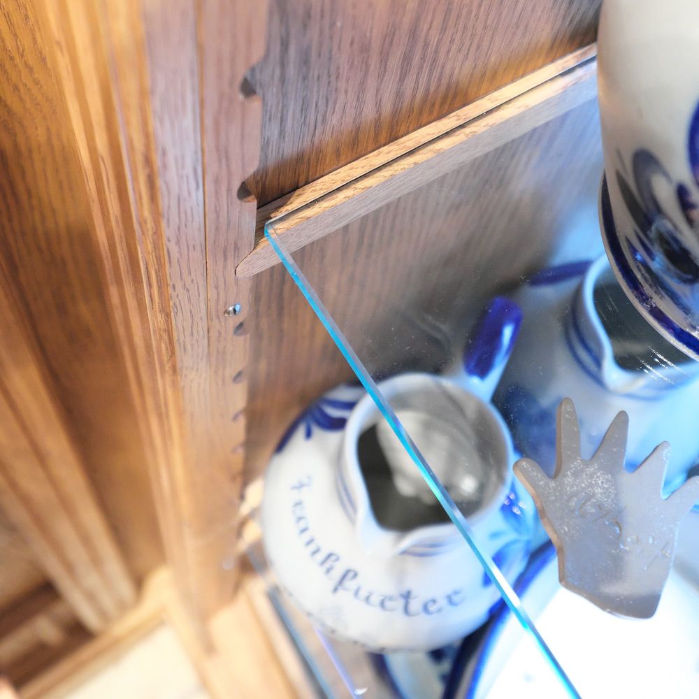 Traditionelle Eichenholz-Vitrine mit gezacktem Regalprofil und blau-weißen Bembel-Krügen
