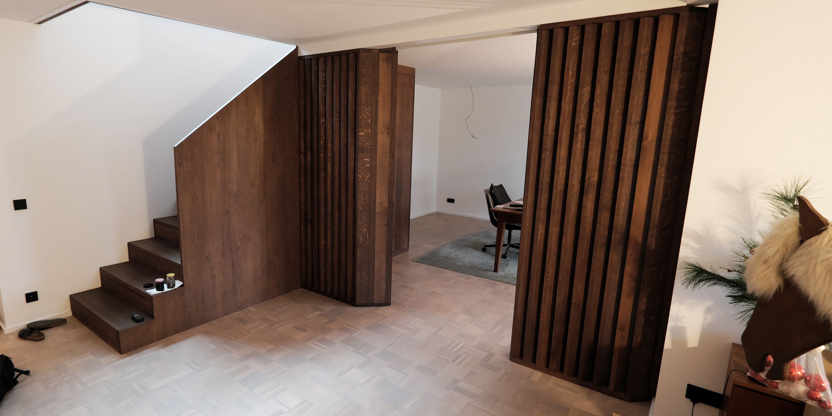 Massivholztreppe mit geöffneter Lamellen-Schiebetür und Blick in ein Arbeitszimmer, dunkel geölte Eiche