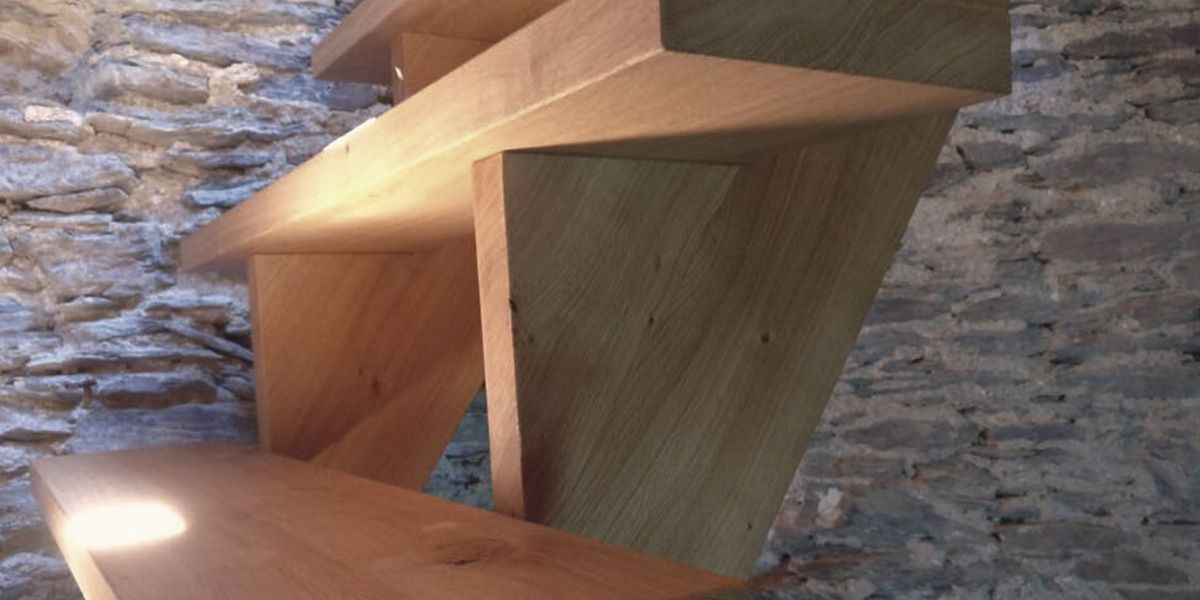 Freitragende Massivholztreppe aus Eiche vor historischer Bruchsteinwand im Bunkerturm