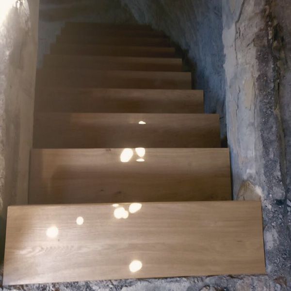 Massivholztreppe aus Eiche in historischem Bunkerturm mit rauer Natursteinwand