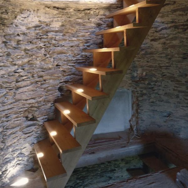 Freitragende Massivholztreppe aus Eiche im Bunkerturm vor rauer Natursteinwand