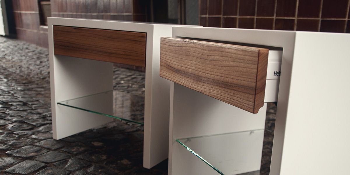 Geöffnete Nussbaum-Schublade eines weißen Nachttisches mit Glasablage im Detail