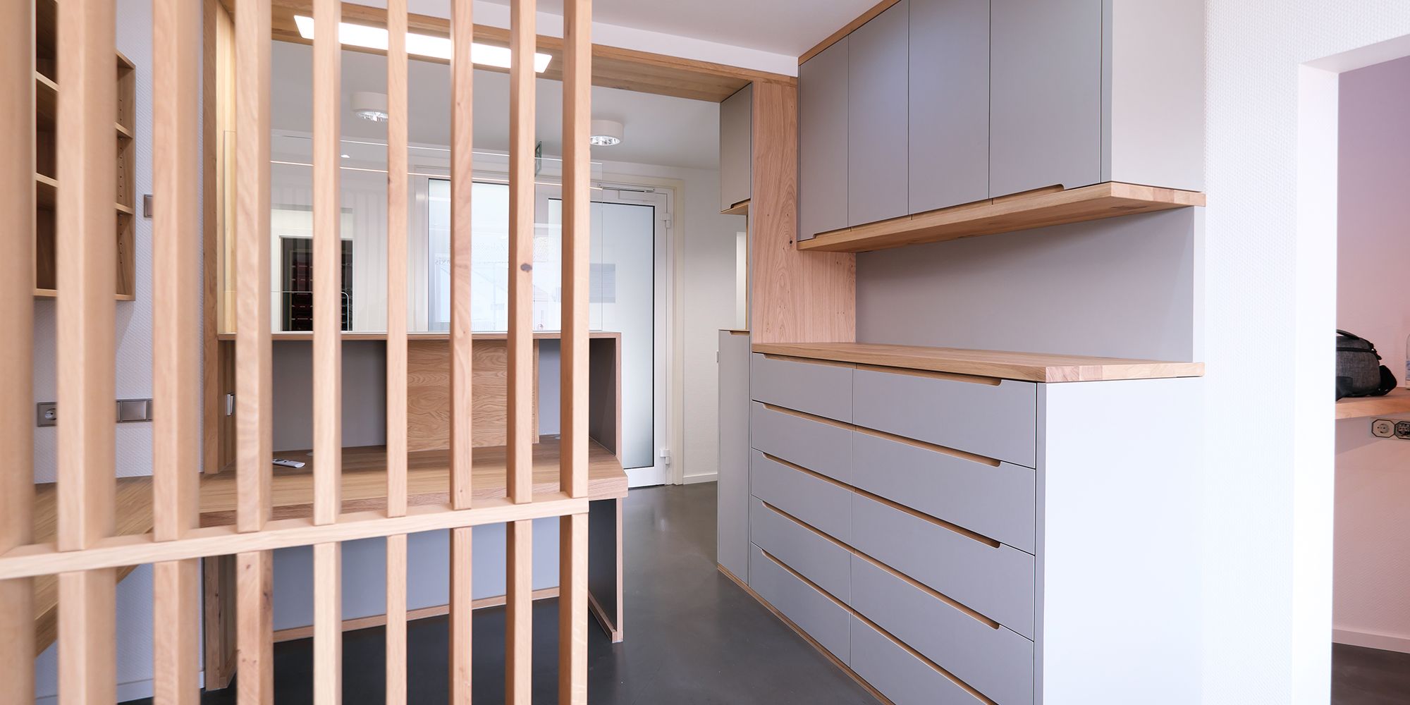 Einbauschrank in Eiche mit Griffleisten und Lamellen-Raumteiler in Praxisflur