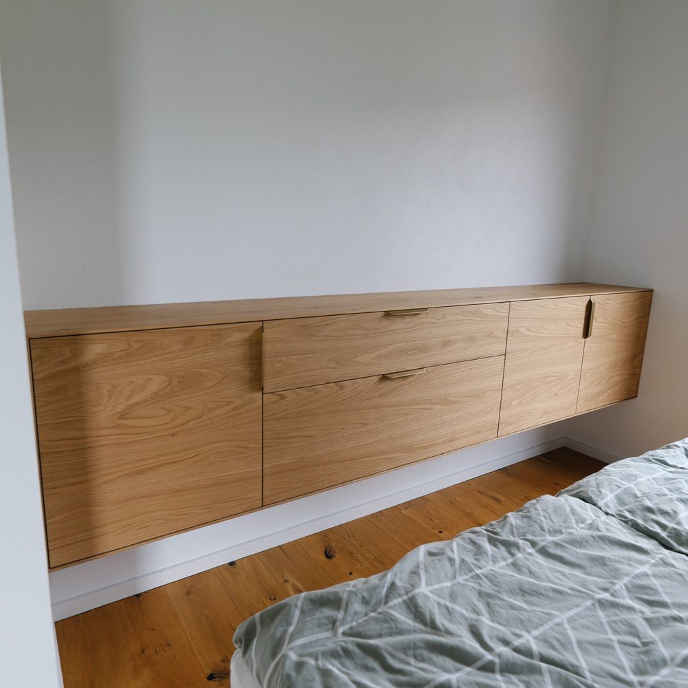 Schwebendes Sideboard aus Eiche mit Messinggriffen über dem Bett im Schlafzimmer