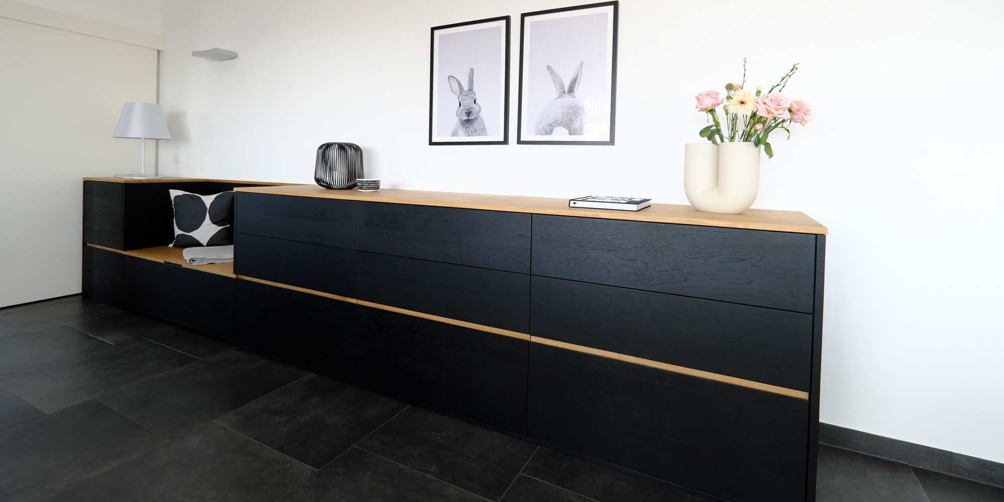 Schwarzes Sideboard aus Massivholz mit Eichenkante, integrierter Sitzbank und Deko im Flur