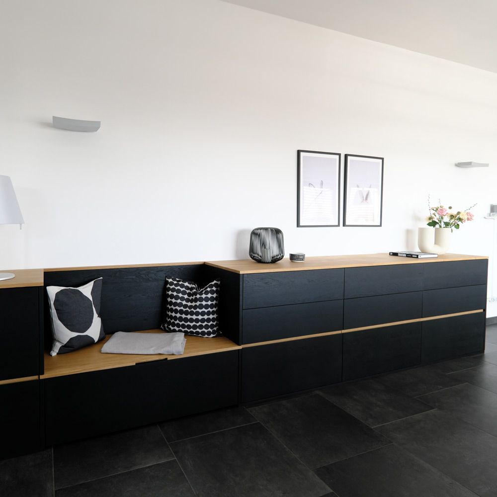 Schwarzes Design-Sideboard mit Eichenholzkante und integrierter Sitzbank im hellen Flur