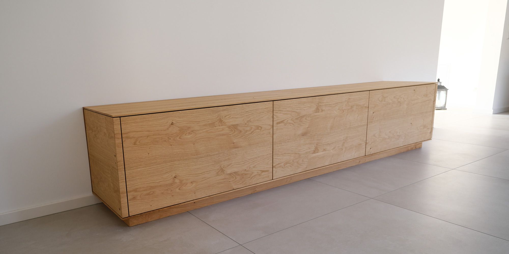 Langgestrecktes Eiche-Sideboard mit filigranen Türen und markanter Maserung im hellen Flur