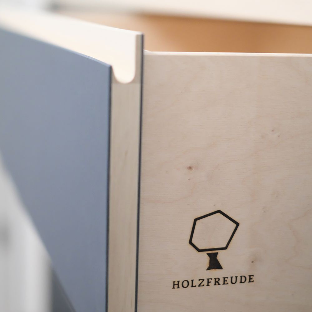 Nahaufnahme Sideboard-Korpus mit eingebrannter Holzfreude-Logogravur und blauer Linoleum-Griffleiste