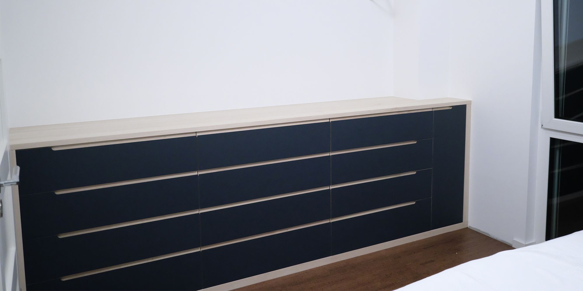 Maßgefertigtes Sideboard aus Hainbuche mit dunkelblauer Linoleumfront im hellen Schlafzimmer