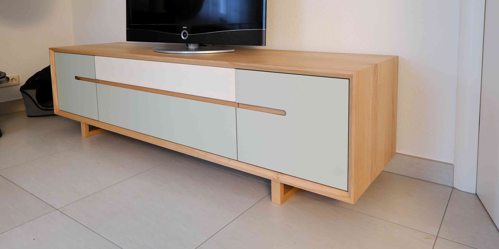 TV-Lowboard aus Kernbuche mit mintfarbener Linoleumfront und Kreuzfüßen im Wohnzimmer
