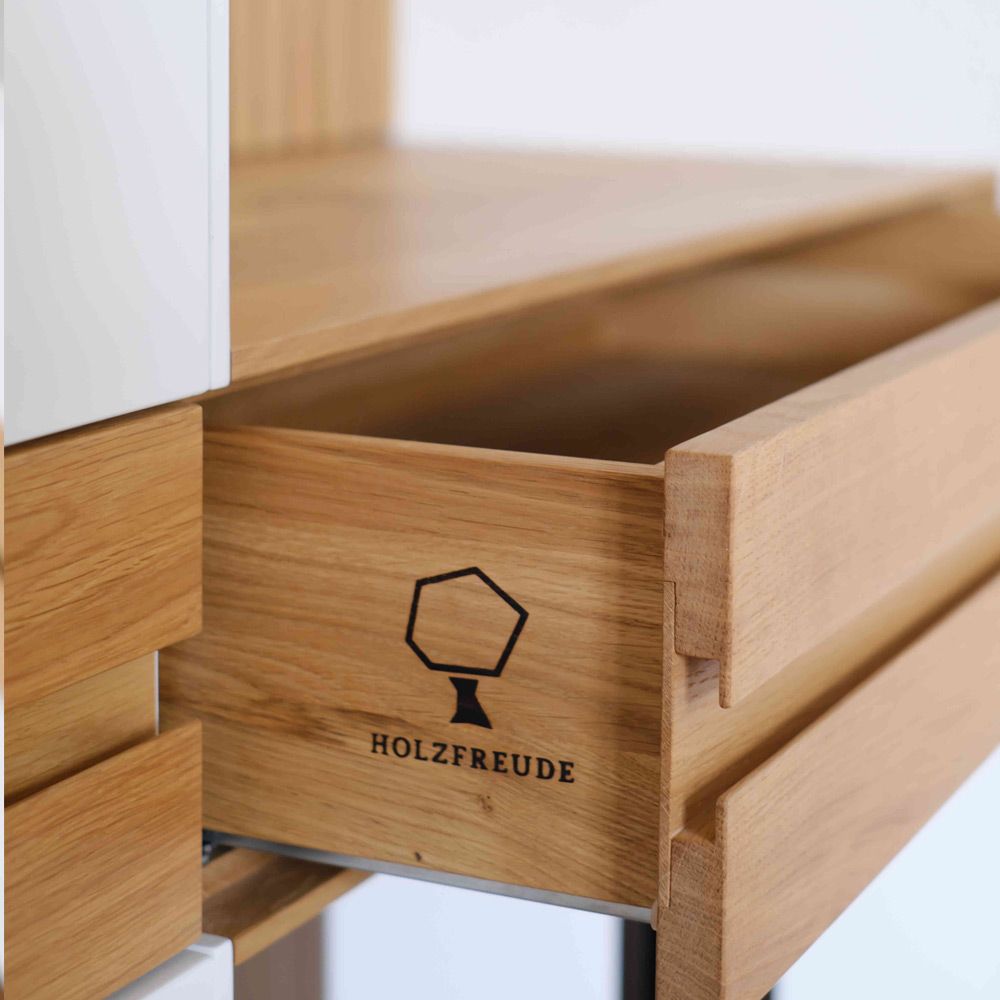 Geöffnete Eiche-Schublade mit sichtbarer Zinkung und Holzfreude-Logogravur an der Lamellenwand