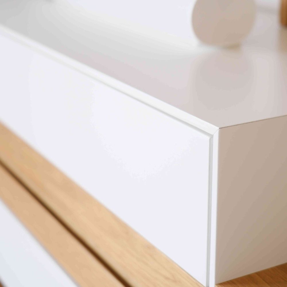 Nahaufnahme einer weiß lackierten Sideboard-Ecke mit präziser Gehrung über Eiche-Lamellensockel