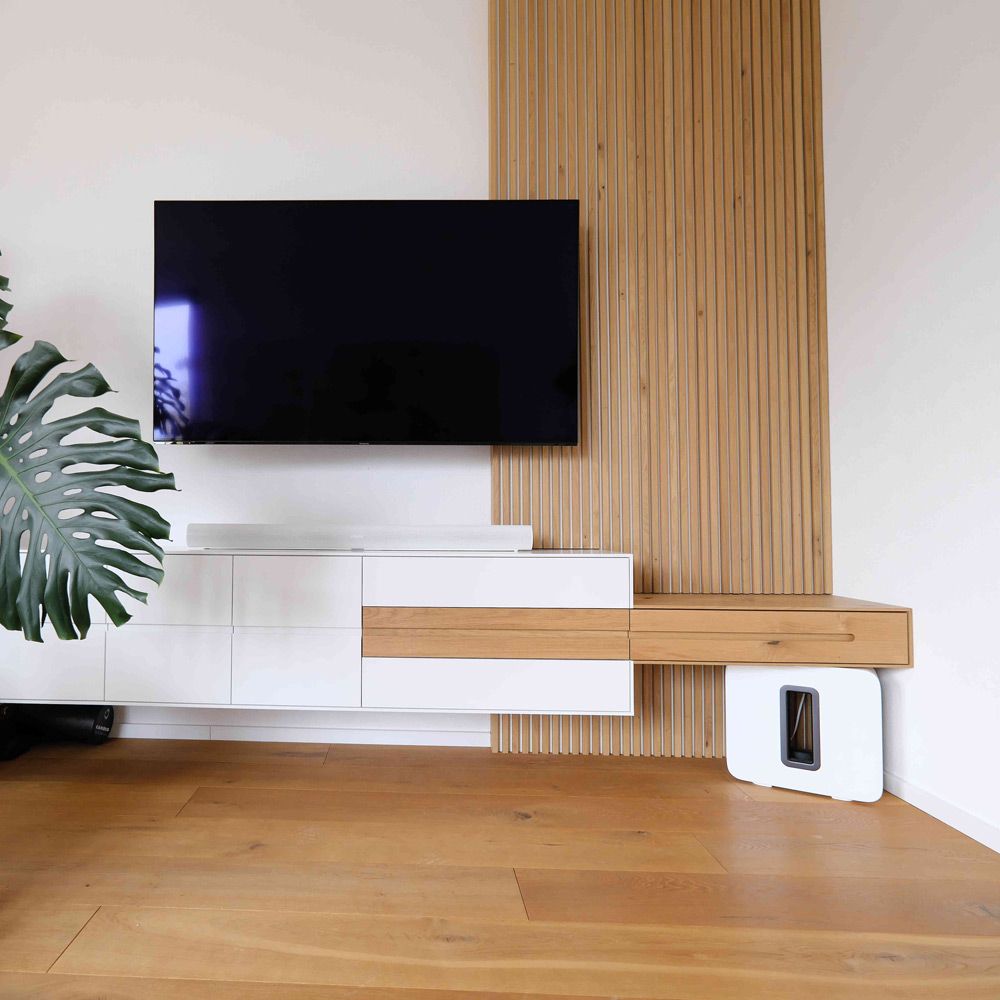 Weißes Lowboard mit Eiche-Lamellenwand als TV-Element im hellen, modernen Wohnzimmer