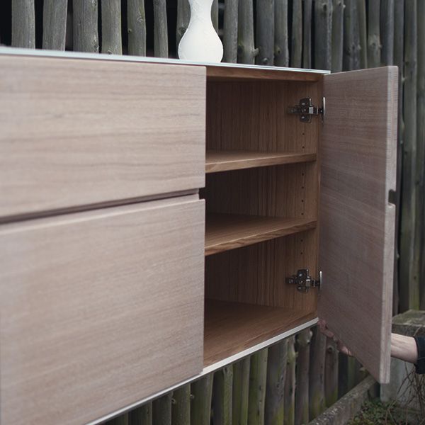 Geöffnete Sideboardtür zeigt Innenraum mit Holzfachböden und Scharnieren im Detail