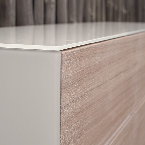 Nahaufnahme der präzisen Eckverbindung zwischen weißer Seitenwange und Holzfront eines Sideboards