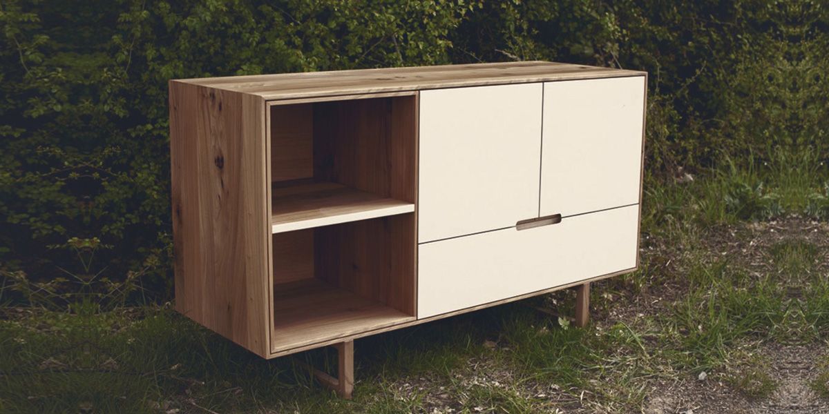 Sideboard aus Massivholz mit offenem Fach und weißen Fronten auf schlanken Beinen im Grünen