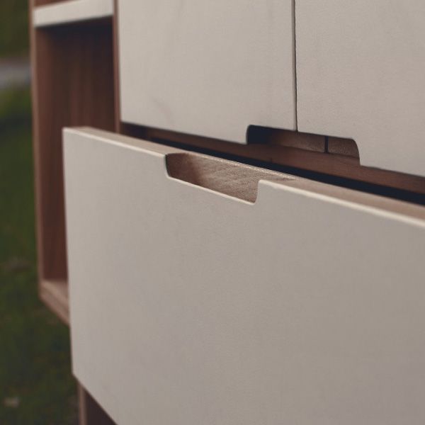 Detailaufnahme des eingefrästen Holzgriffs an weißer Sideboard-Schublade mit Massivholzkante